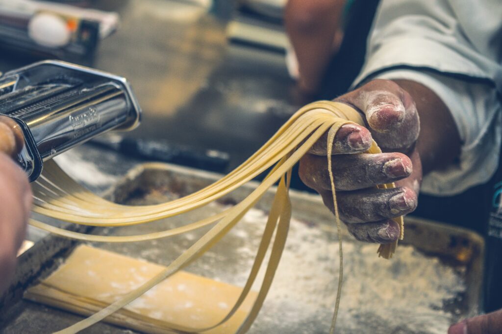 homemade past being pulled through a fettucine noodle cutter