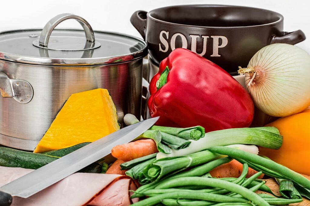 soup bowls, a large pot with various vegetables sitting in front